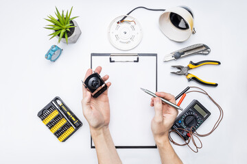 cctv camera service repair concept. above view. handyman adjusting surveillance camera using tools on white desk