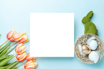 Wall Mural - Easter decoration. Golden, white colour egg in basket with spring tulips, feathers on pastel blue background in Happy Easter decoration. Foil minimalist egg design with copy space.