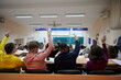 © .shock - Raised hands and arms of large group of people in class room