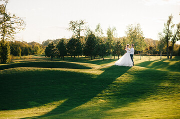 Happy husband and wife. Wedding day. Beautiful nature. Walk during the photo session. They smile at each other. Holding hands.