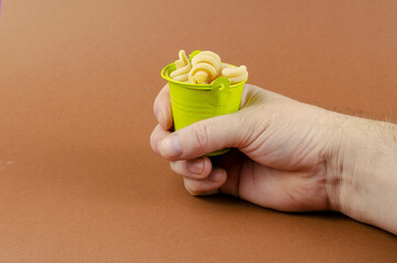 Green metal bucket, dry insalatonde pasta and hand on a brown ba