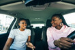 © F8  \ Suport Ukraine - Two attractive young african girlfriends talking and laughing together while driving in a car through the city on a sunny day.