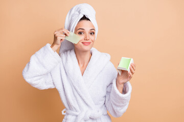 Wall Mural - Photo of happy joyful young woman apply paper oily skin cosmetology isolated on pastel beige color background