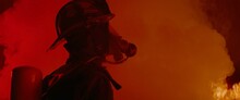 Dramatic Silhouette Of American Firefighter In Full Gear Exploring The Huge Fire Zone