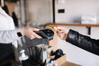 © Aleksandr - Female customer making wireless or contactless payment using credit card. Closeup of human hands during payment. Store worker accepting payment over nfc technology. Side view