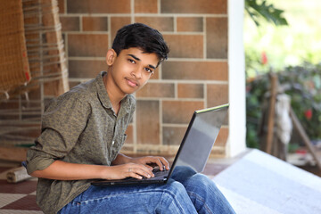 Wall Mural - Portrait of Indian boy using laptop while attending the online classes at home	
