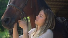 Close Up Of Young Woman Preparing Her Horse, Putting Bridle And Harness. Woman Fixing Mane From Harness In A Riding School