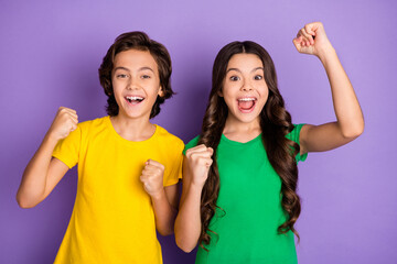 Photo of two excited preteen girl boy happy positive smile celebrate win victory fists hands isolated over violet color background