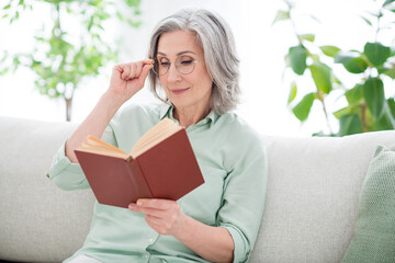 Sticker - Portrait of charming aged person sit on sofa arm touch glasses look reading book vacation home indoors