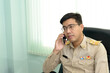 © ULTRAPOK - A Thai government officer, Civil servant is making a phone call at the office.