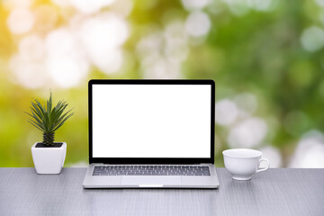 Laptop and cup of coffee with green bokeh nature background