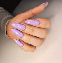 Solid Purple Gel Polish On Very Long Nails Without Design. Women's Hands With A Lilac Manicure. The Coating Is Light Purple On The Nails.