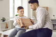 © Studio Romantic - Young man getting birthday gift and thanking his little son for surprise. Child giving present box to his dad and wishing him Happy Father's Day. Exchanging presents on special family occasion concept