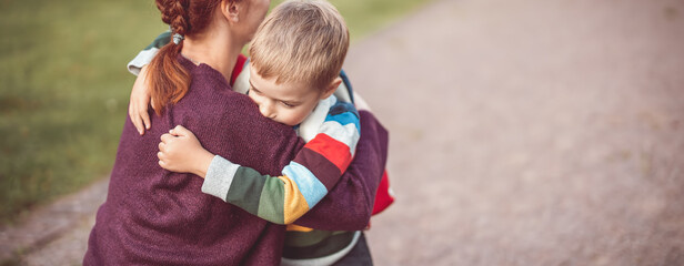 Child with rucksack and with mother in front of a school building