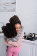 © LIGHTFIELD STUDIOS - happy african american woman with closed eyes hugging daughter in kitchen
