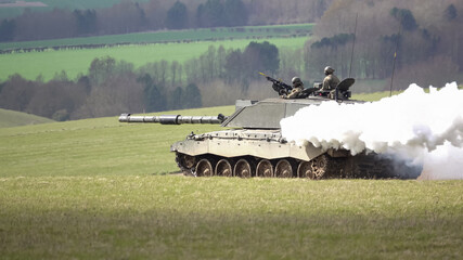 a british army challenger ii main battle tank creating a thick white smoke screen whilst on maneuver