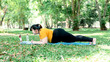 Asian attractive fat woman lose weight by exercising in the park By practicing Plank pose, by teaching online, to people and education online concept.