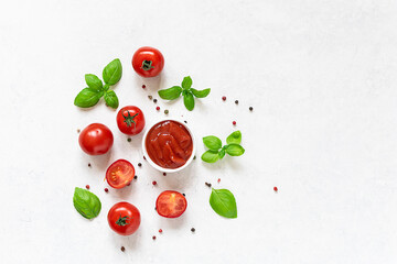 Fresh homemade tomato sauce or ketchup with peppercorn and aromatic basil on white marble background with copy space for your design.