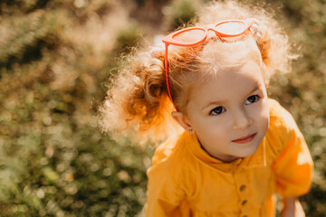 Portrait photos caucasian kid girls aged 2 to 4 years with curly hair, cute face, smiling, who looks up at the person who is photographing her