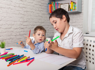 Happy children draw in the classroom. The child learns at home. Home schooling. Brothers drawing pictures at kindergarten. Boys going to be a painter, artist, talent concept. Creative little boys