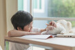 © lalalululala - Happy Asian child playing with pet cat while doing homework