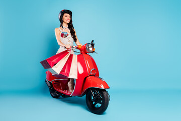 Sticker - Portrait of attractive cheerful girl riding moped delivering bringing new things isolated on bright blue color background