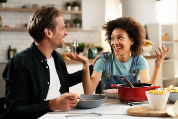 Wall Mural - Boyfriend and girlfriend eating lunch together at home. Husband and wife enjoying in delicious food.