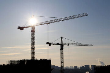 Wall Mural - Tower cranes and construction site on sunshine background. Housing development, apartment block in city