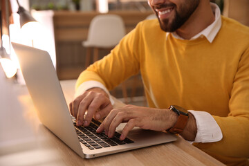 Poster - Man working with laptop at table in cafe, closeup