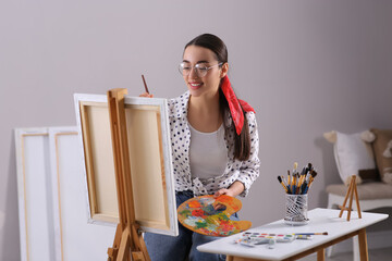 Sticker - Happy woman artist drawing picture on canvas indoors