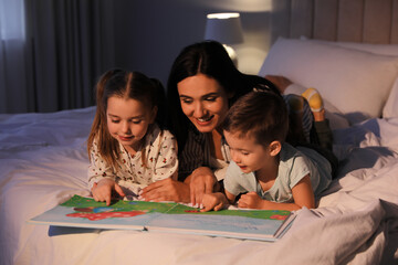 Wall Mural - Mother reading bedtime story to her children at home