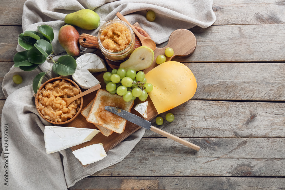 Tasty pear jam with different cheeses and bread on wooden background