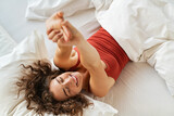 Happy smiling woman stretching on bed in the morning