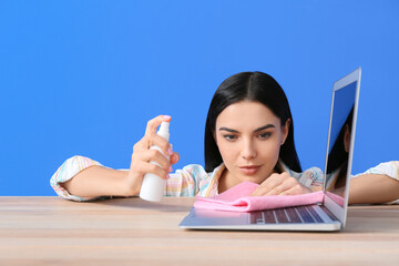 Sticker - Young woman cleaning laptop on color background