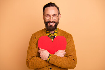 Poster - Photo of positive mature man embrace big red paper card heart isolated over beige color background