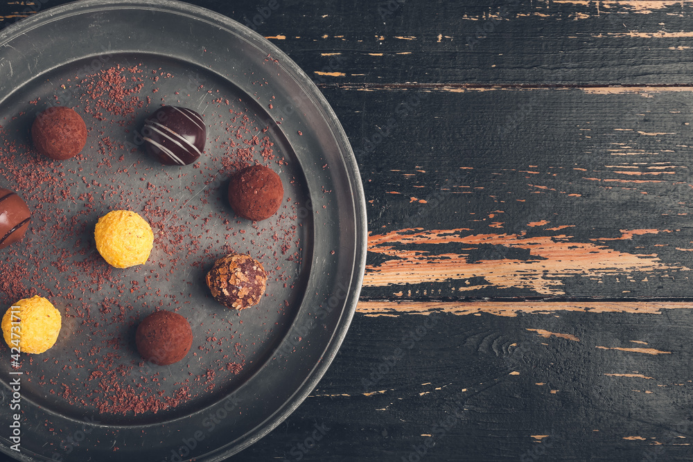 Plate with sweet chocolate candies on wooden background