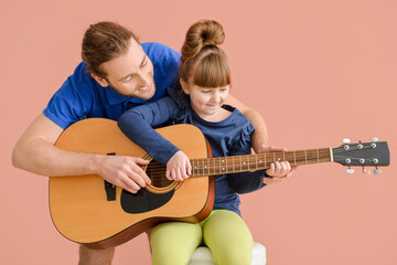 Wall Mural - Father and daughter playing guitar on color background