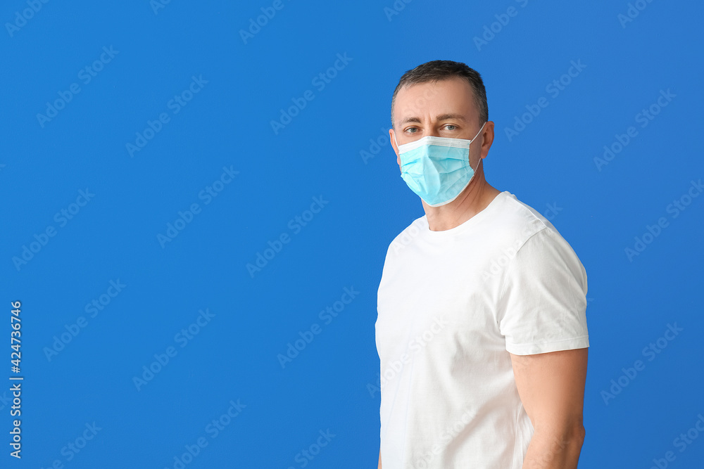 Mature man in medical mask on color background