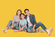 © Tom Wang - Happy Asian young family with one child sitting  and smiling at camera isolated on yellow