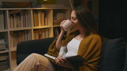 Wall Mural - woman reading book and drinking coffee at home.evening scene