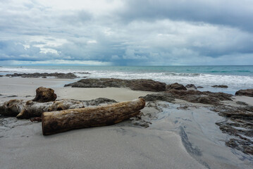 Rocks and a log on a stormy beach in Costa Rica 