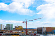 © Lena_viridis - Construction of a new multistory building in the city, red construction crane on a blue cloudy sky background, construction site, New High-Rise Buildings