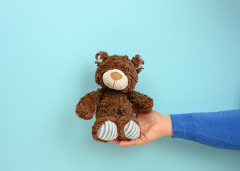 Wall Mural - female hand hold a small brown toy teddy bear