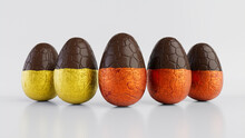 Easter Eggs Isolated Against A White Background. Partially Unwrapped Chocolate Eggs With Patterned Orange And Yellow Foil. 3D Render