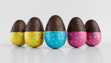 Easter Eggs Isolated Against A White Background. Partially Unwrapped Chocolate Eggs With Patterned Blue, Yellow And Pink Foil. 3D Render