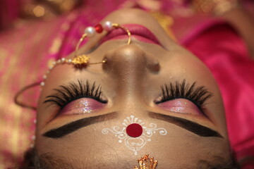 Closeup Portrait of an beautiful woman Indian model in Bridal look with heavy gold jewelry and red sari.