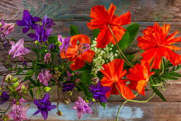Wall Mural - bouquets of aquilegia flowers and red poppies on a wooden background close-up top view