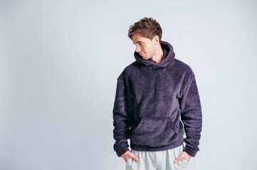 Wall Mural - Portrait of a young man in purple sweatshirt with hood on a white background. Copy, empty space for text