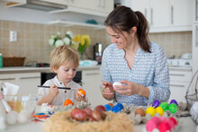 Beautiful Blond Child, Toddler Boy, Painting Easter Eggs With Mother At Home, Making Easter Wreath