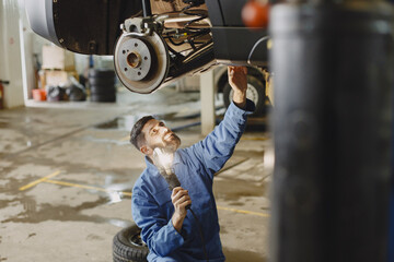 Canvas Print - Checking car for serviceability in garage with tools on hoist